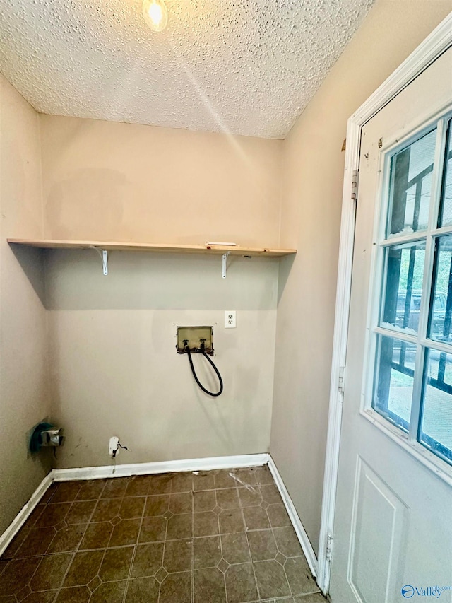 laundry room with dark tile patterned flooring, a textured ceiling, electric dryer hookup, and hookup for a washing machine