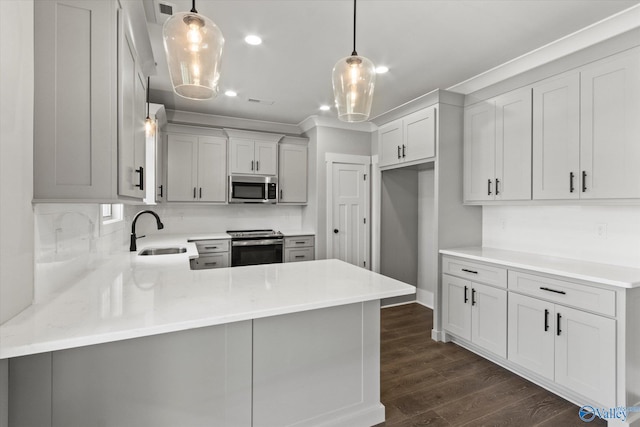 kitchen featuring dark wood-type flooring, appliances with stainless steel finishes, sink, and pendant lighting