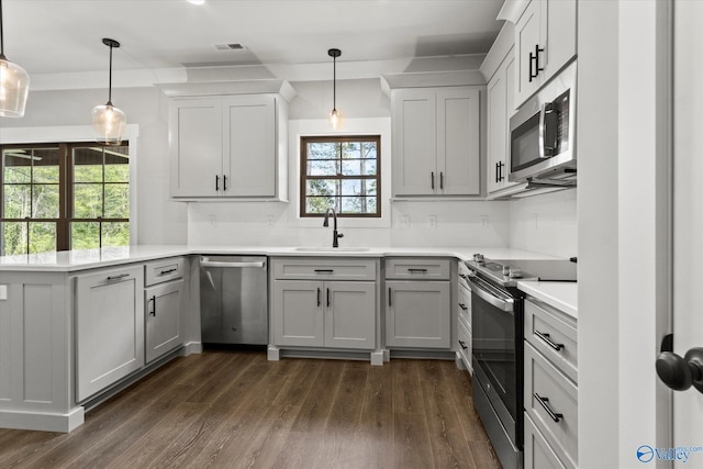 kitchen with dark hardwood / wood-style flooring, stainless steel appliances, gray cabinetry, and decorative light fixtures