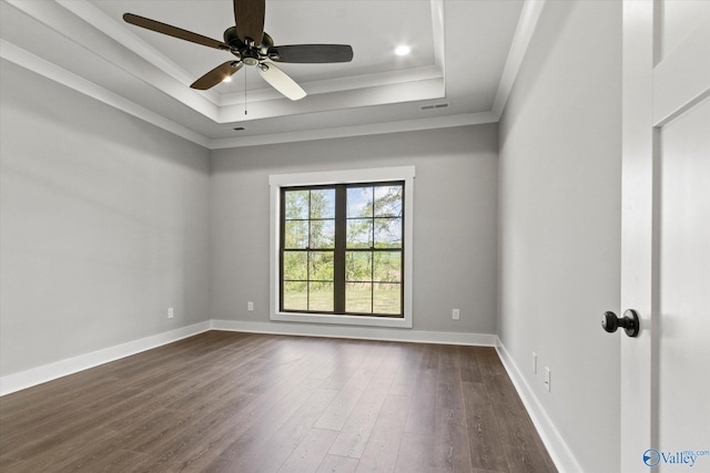 spare room with ornamental molding, ceiling fan, a raised ceiling, and dark wood-type flooring