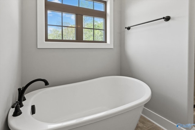 bathroom with tile patterned flooring, a wealth of natural light, and a bathtub