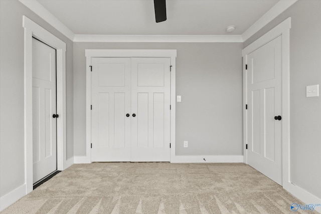 unfurnished bedroom with a closet, crown molding, ceiling fan, and light colored carpet