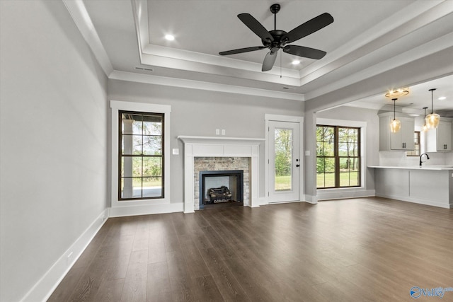 unfurnished living room with a raised ceiling, sink, ceiling fan, and hardwood / wood-style floors