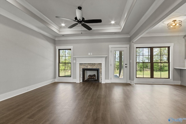 unfurnished living room with ornamental molding, dark wood-type flooring, ceiling fan, and a tray ceiling