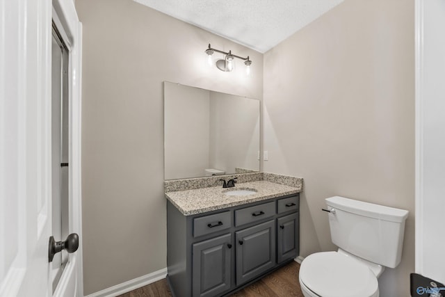 bathroom featuring hardwood / wood-style floors, toilet, vanity, and a textured ceiling