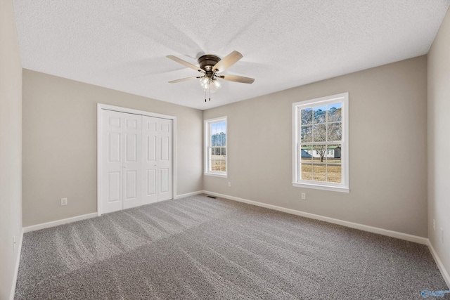 unfurnished bedroom featuring ceiling fan, a textured ceiling, a closet, and carpet flooring