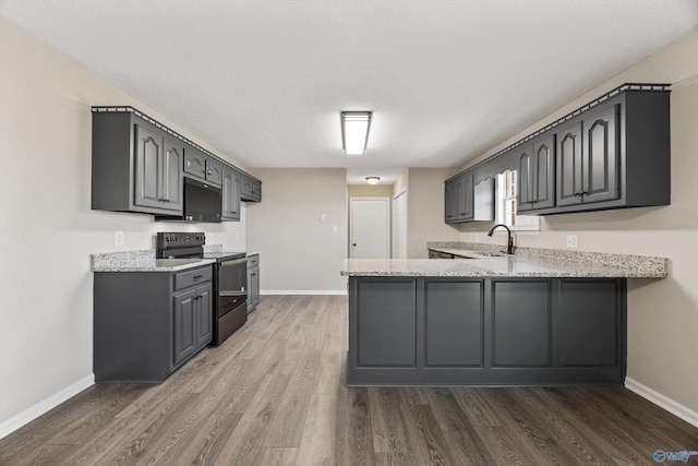 kitchen featuring gray cabinets, dark hardwood / wood-style flooring, electric range, and light stone counters