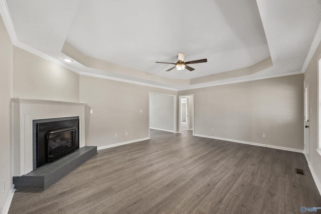 unfurnished living room featuring ceiling fan, a brick fireplace, a raised ceiling, and wood-type flooring