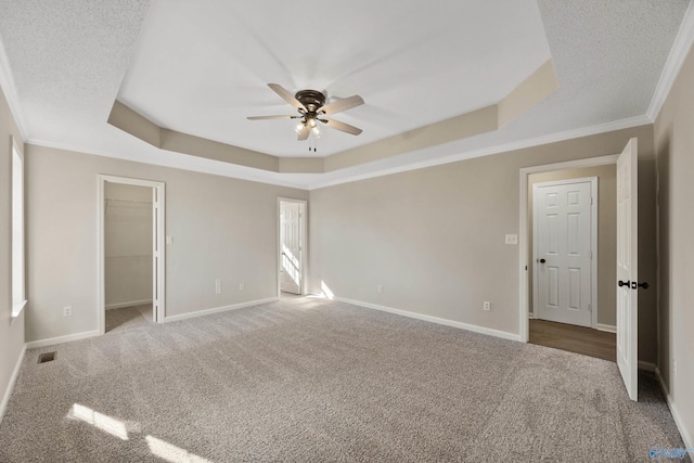 interior space with crown molding, carpet flooring, a textured ceiling, and a tray ceiling