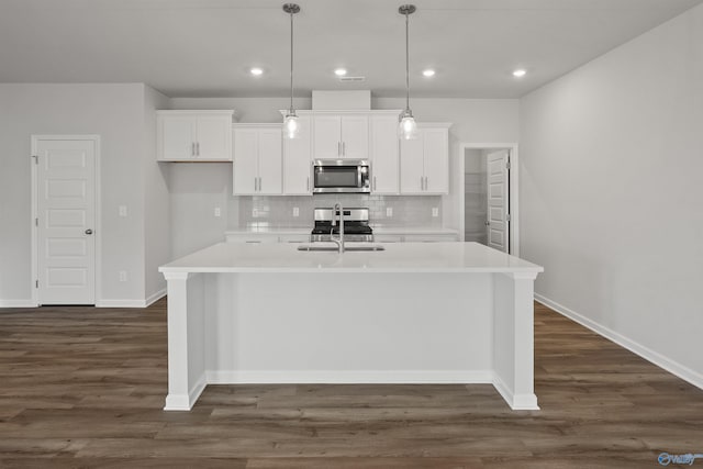 kitchen with dark hardwood / wood-style flooring, stainless steel appliances, a kitchen island with sink, white cabinetry, and decorative backsplash