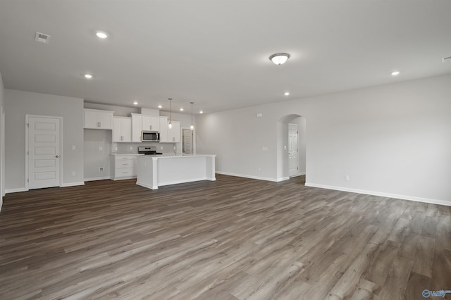 kitchen featuring stainless steel appliances, dark hardwood / wood-style flooring, pendant lighting, an island with sink, and white cabinetry