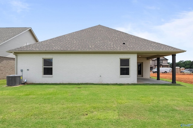 back of house with central air condition unit and a yard