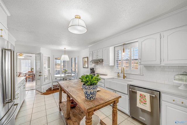 kitchen featuring light tile patterned flooring, stainless steel appliances, white cabinetry, pendant lighting, and a healthy amount of sunlight