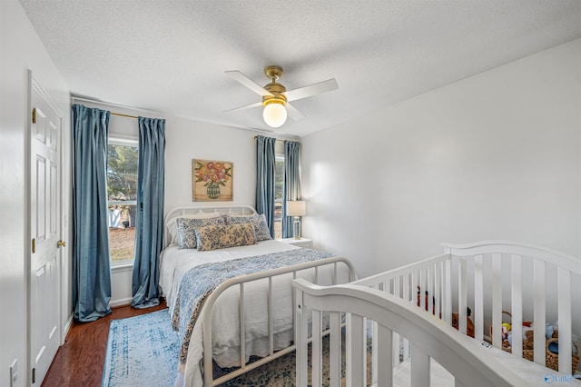 bedroom with a textured ceiling, dark wood-type flooring, and ceiling fan