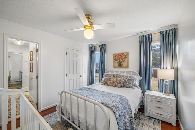 bedroom with dark wood-type flooring, a textured ceiling, and ceiling fan