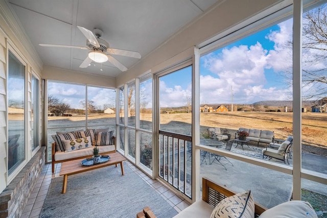 sunroom / solarium featuring a healthy amount of sunlight, a rural view, and ceiling fan