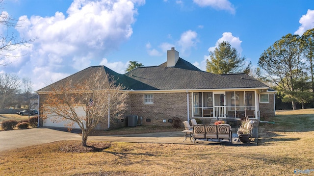 rear view of house featuring a patio, a lawn, a garage, central air condition unit, and a sunroom