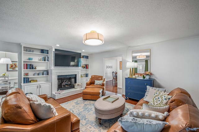 living room with hardwood / wood-style flooring, built in features, a textured ceiling, and a fireplace