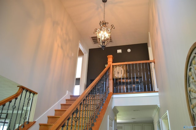 stairway with a chandelier and a towering ceiling