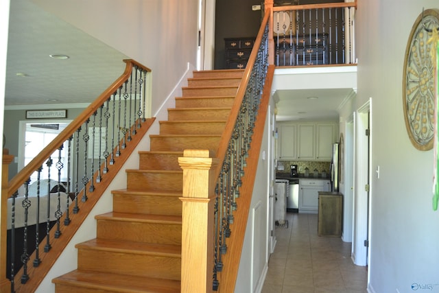 staircase with tile patterned floors and crown molding