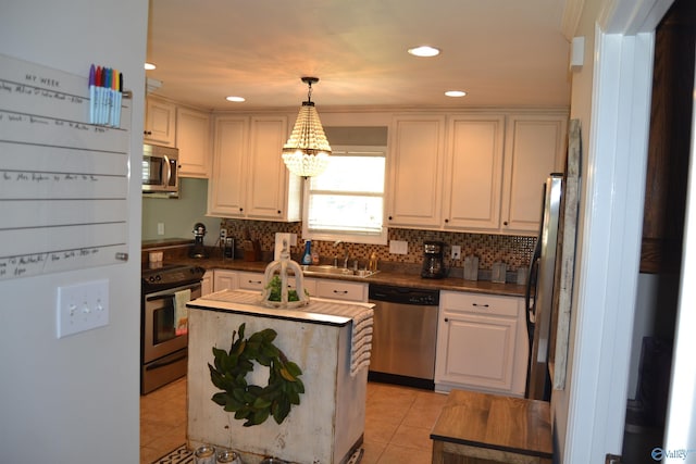 kitchen with sink, stainless steel appliances, hanging light fixtures, and white cabinets