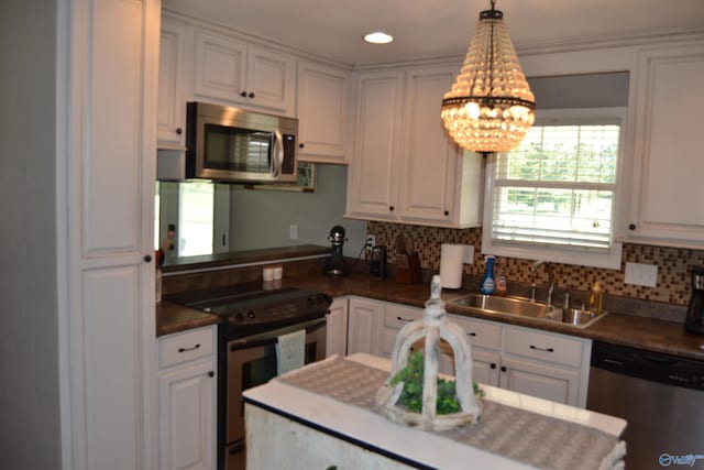 kitchen with sink, hanging light fixtures, white cabinets, and appliances with stainless steel finishes