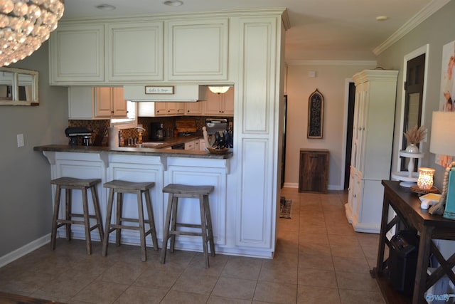 kitchen with backsplash, ornamental molding, kitchen peninsula, a breakfast bar, and light tile patterned floors