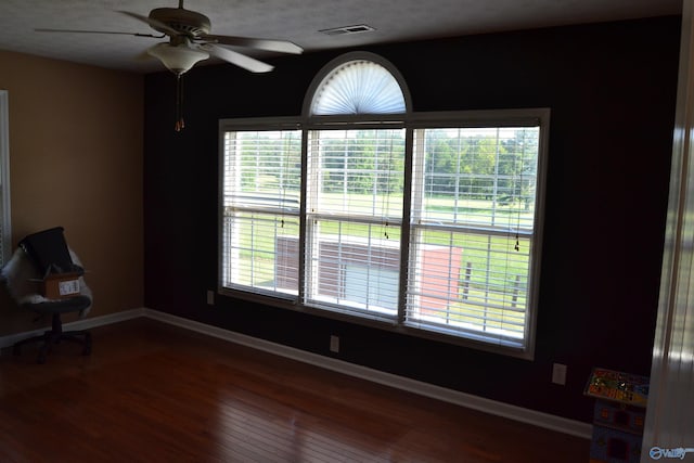 empty room with plenty of natural light, hardwood / wood-style flooring, and ceiling fan