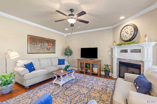 living area with dark wood finished floors, a fireplace, ornamental molding, a ceiling fan, and baseboards