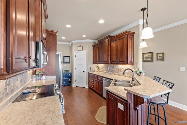 kitchen with stainless steel appliances, light countertops, hanging light fixtures, a sink, and a kitchen breakfast bar