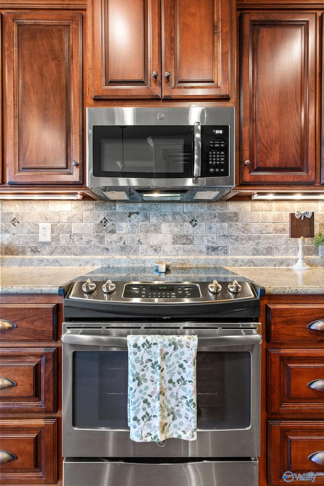 kitchen featuring stainless steel appliances, tasteful backsplash, and light stone counters