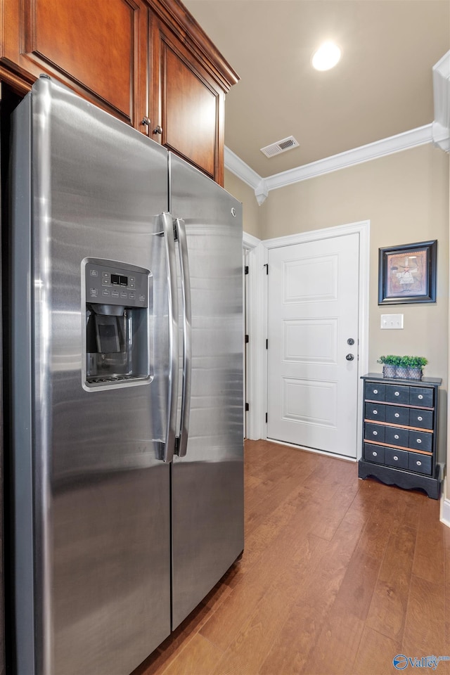 kitchen with crown molding, wood finished floors, visible vents, and stainless steel fridge with ice dispenser