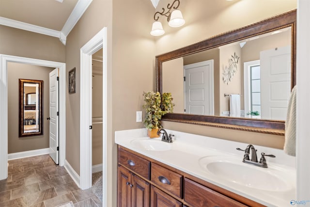 full bath featuring double vanity, crown molding, baseboards, and a sink