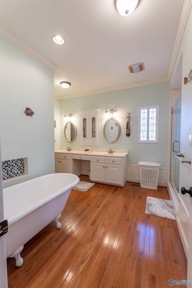 full bathroom with a freestanding tub, a sink, wood finished floors, double vanity, and crown molding