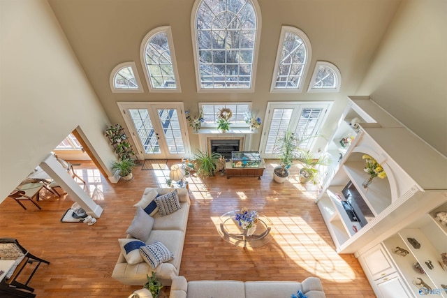 living room with a wealth of natural light, french doors, a towering ceiling, and wood finished floors