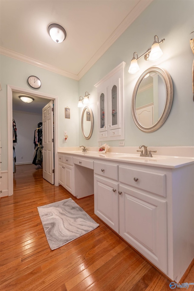 full bath with a walk in closet, double vanity, ornamental molding, a sink, and wood finished floors