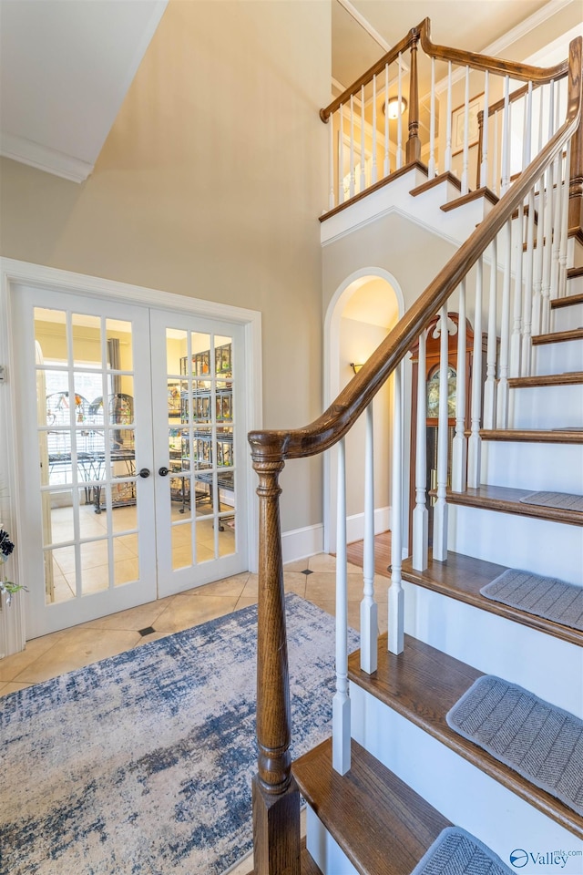 stairway with a high ceiling, visible vents, baseboards, french doors, and tile patterned floors