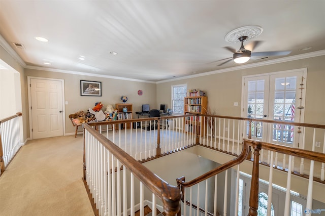 corridor featuring light colored carpet, visible vents, an upstairs landing, french doors, and crown molding