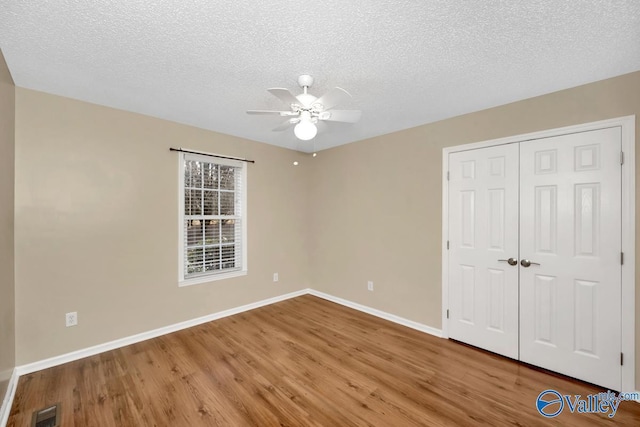 unfurnished bedroom featuring ceiling fan, hardwood / wood-style floors, a closet, and a textured ceiling