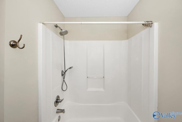 bathroom featuring washtub / shower combination and a textured ceiling