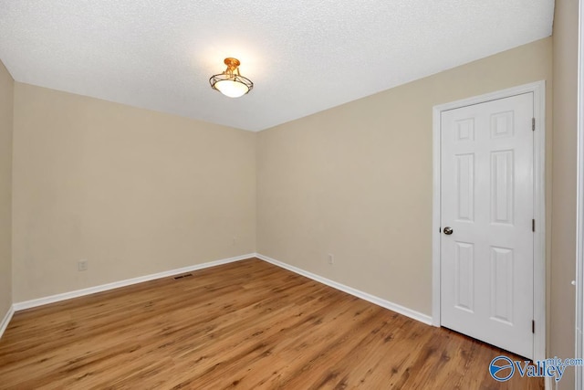 unfurnished room with hardwood / wood-style flooring and a textured ceiling