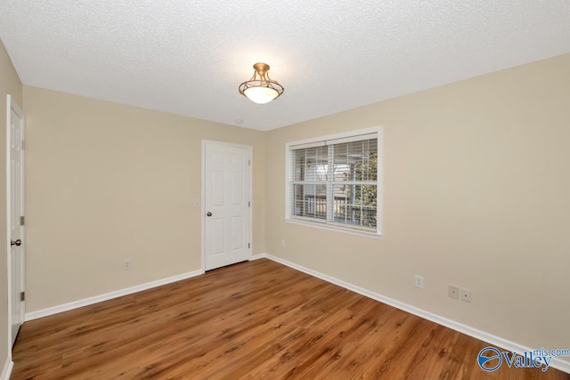 empty room with hardwood / wood-style flooring and a textured ceiling