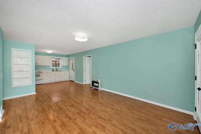 unfurnished living room with heating unit, sink, light wood-type flooring, a textured ceiling, and built in shelves