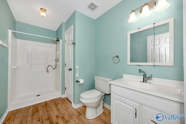 bathroom with walk in shower, vanity, a textured ceiling, and hardwood / wood-style flooring