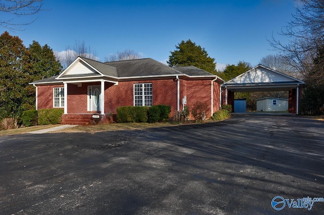 view of front of home with a carport and a storage unit