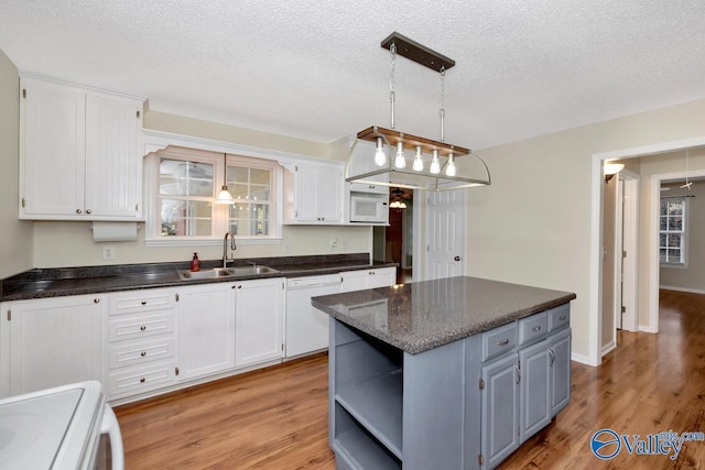 kitchen featuring sink, a textured ceiling, white appliances, light hardwood / wood-style floors, and white cabinets