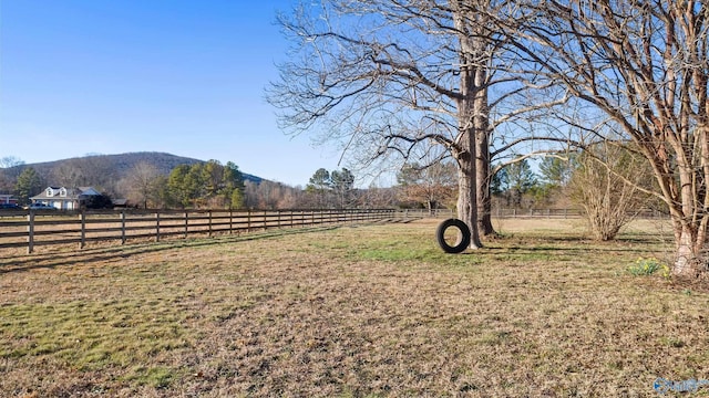 view of yard with a rural view, a mountain view, and fence