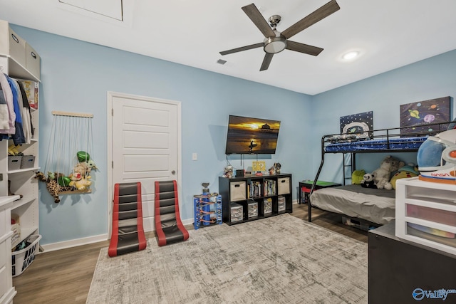 bedroom with ceiling fan, wood finished floors, visible vents, and baseboards