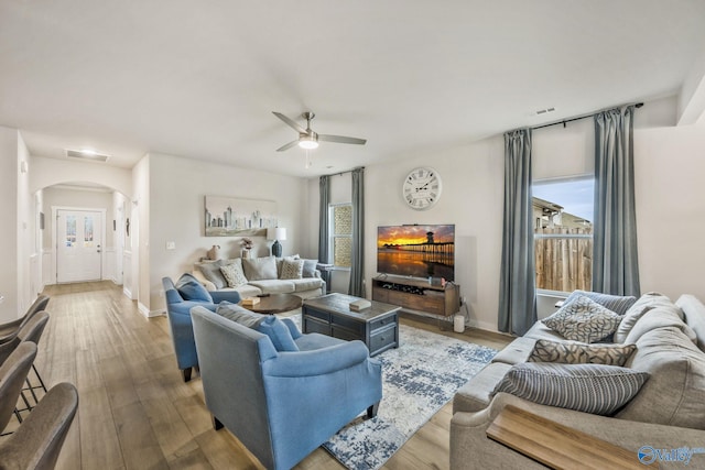 living area with arched walkways, wood finished floors, visible vents, and a healthy amount of sunlight