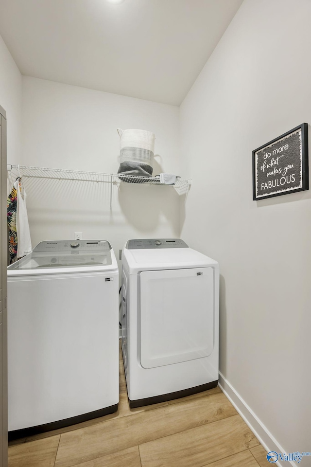 laundry room featuring laundry area, light wood finished floors, washing machine and clothes dryer, and baseboards